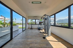 Un vaste balcon doté d’une salle de sport, de grandes fenêtres et offrant une vue sur la ville.