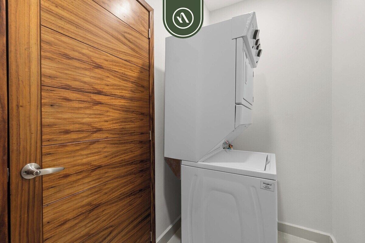 A wooden door with a metal handle, a white appliance with a control panel, and a green directional sign above.
