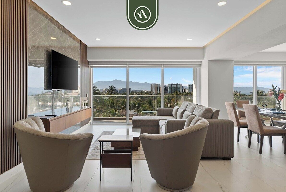 A modern living room with a sofa set, a TV, and a dining area with chairs and a table.