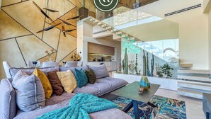 A modern living room with a sectional sofa, a coffee table, and a staircase leading to an upper level. - Two Story 2 BR Penthouse - Pool - Ocean View (Puerto Vallarta)