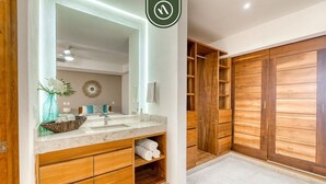 A bathroom with a large mirror, wooden cabinetry, and a vanity with a sink. - Luxury 4 BR Condo - Amazing Bay View - Pool (Acapulco)