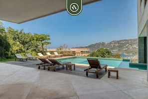 Un espace aménagé au bord de la piscine, avec des chaises longues et une vue sur le paysage.