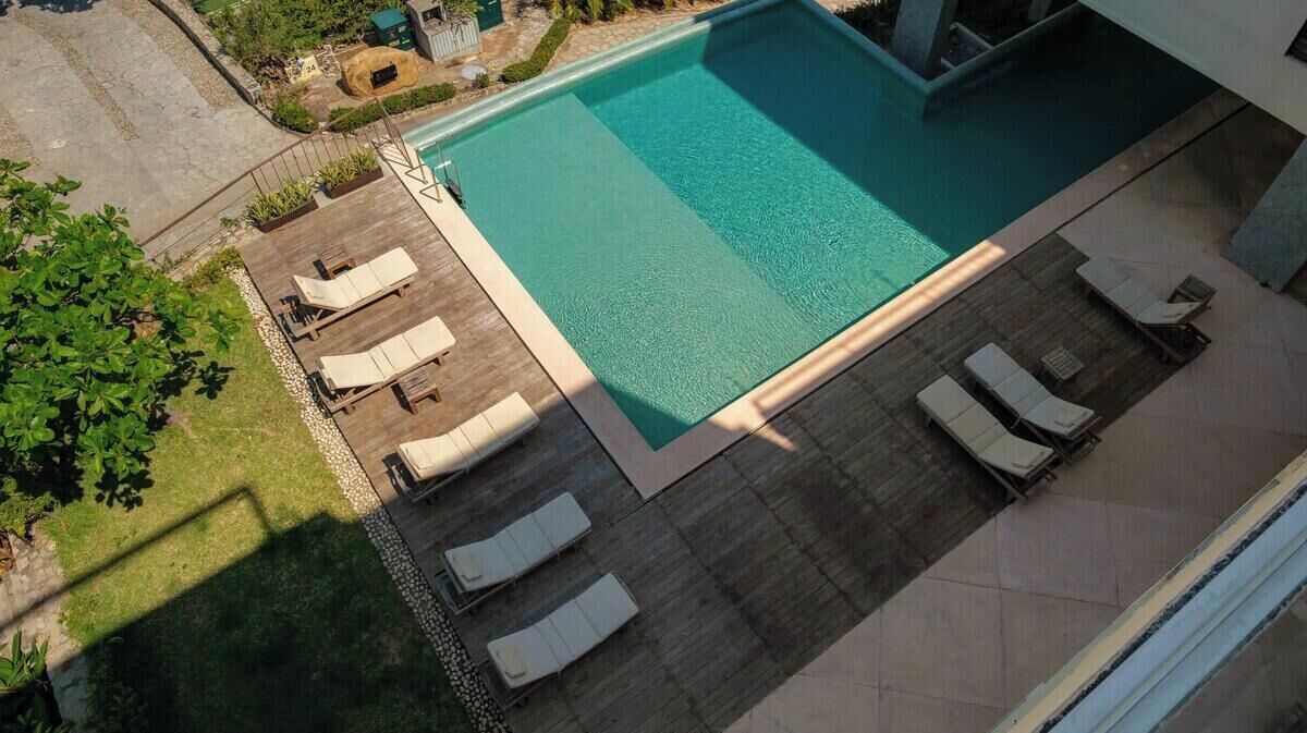 A rectangular swimming pool with lounge chairs and a wooden deck.