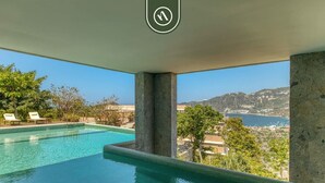 A swimming pool with a view of a mountainous landscape and a body of water. - Luxury 4 BR Condo - Amazing Bay View - Pool (Acapulco)