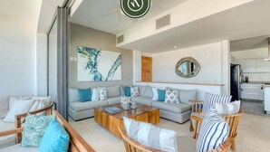A modern living room with a sofa, coffee table, and wicker chairs. - Luxury 4 BR Condo - Amazing Bay View - Pool (Acapulco)