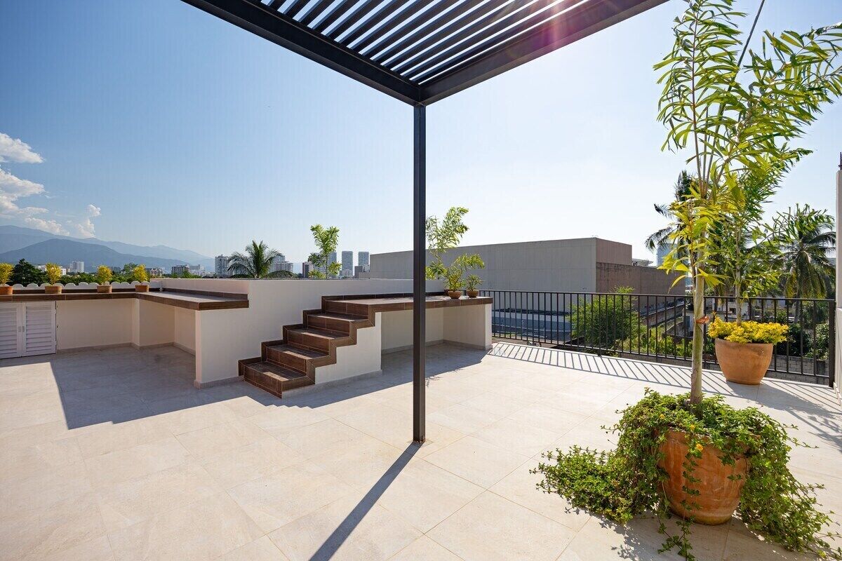 A rooftop terrace with a pergola, a staircase, and potted plants.