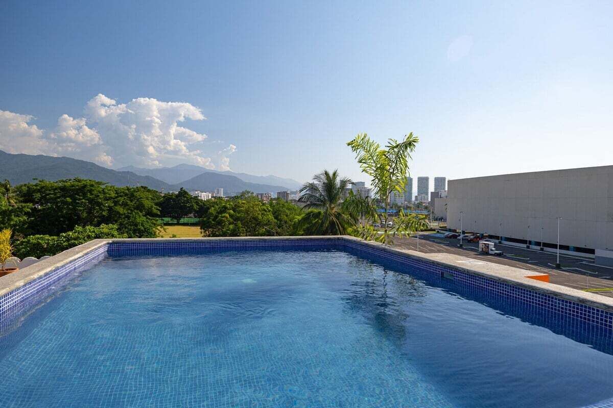 A swimming pool with a clear view of mountains and a parking area in the background.