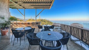 An outdoor patio with round tables and chairs, overlooking a scenic ocean view. - 3 BR Condo - Private Terrace and Pool - Oceanview (Puerto Vallarta)