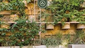 A building with a water feature, climbing plants, and a sign with a symbol. - 3 BR Condo - Private Terrace and Pool - Oceanview (Puerto Vallarta)