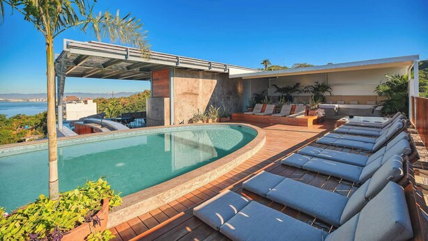 A modern pool area with lounge chairs, a covered seating area, and a view of the sea. - 3 BR Condo - Private Terrace and Pool - Oceanview (Puerto Vallarta)