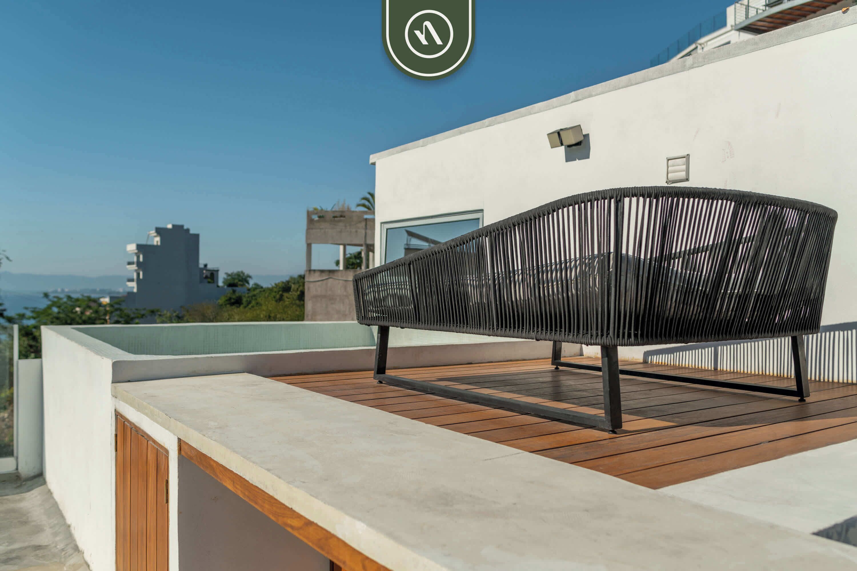 Een moderne buiten zithoek met een houten terras en een metalen stoel.