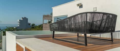 A modern outdoor seating area with a wooden deck and a metal chair.