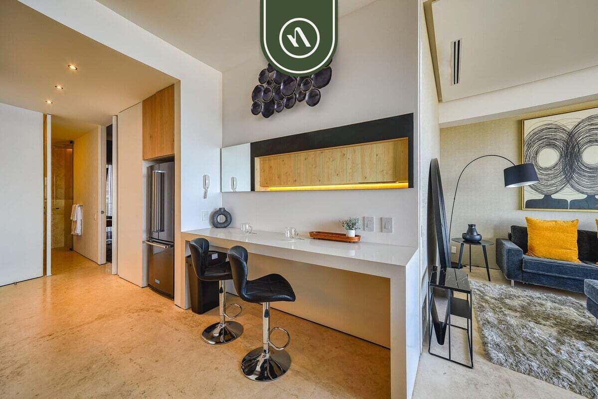 A modern kitchen with a central island, two bar stools, a refrigerator, and a wooden cabinet.