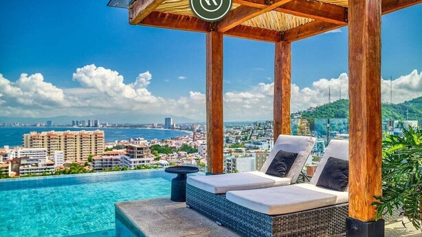 An infinity pool with lounge chairs and a view of a cityscape and ocean. - Luxury Studio in Romantic Zone - Infinity Pool (Puerto Vallarta)