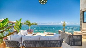 A rooftop terrace with a sofa and chairs facing a clear view of the ocean. - Luxury Studio in Romantic Zone - Infinity Pool (Puerto Vallarta)