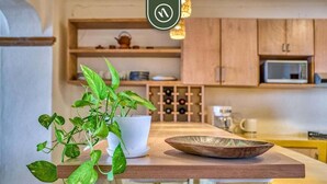 A kitchen with wooden cabinets, a white countertop, a potted plant, a bowl, and a wine rack. - Brand New 2BR Condo With Oceanview - Terrace (Puerto Vallarta)