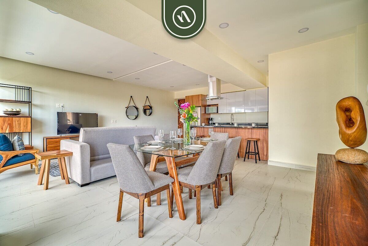 A modern living room with a dining area, a kitchen, and a TV.