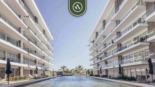 A modern hotel with a central swimming pool, multiple balconies, and outdoor seating areas.