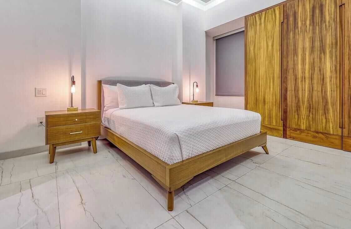 A bedroom with a wooden bed, bedside tables, a wardrobe, and a skylight.