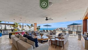 A spacious outdoor lounge area with seating, a pool, and a view of the ocean. - Elegant Studio in Romantic Zone - Rooftop Pool (Puerto Vallarta)