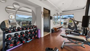 A modern gym with exercise equipment, a rack of dumbbells, and large mirrors. - Elegant Studio in Romantic Zone - Rooftop Pool (Puerto Vallarta)