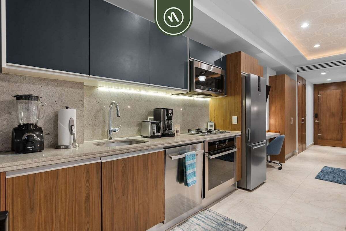 A modern kitchen with dark cabinets, stainless steel appliances, and a built-in oven.