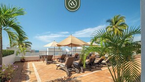 A rooftop terrace with lounge chairs, umbrellas, and potted plants. - Amazing 2 BR Condo Overlooking the Pool - Romantic Zone (Puerto Vallarta)