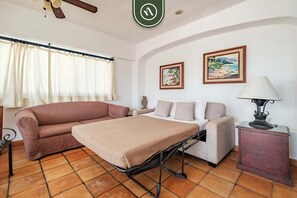 Una habitación con cama, sofá, mesa y dos cuadros en la pared.