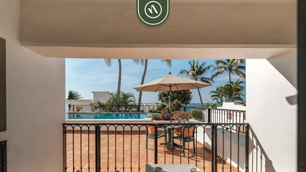 A balcony with a pool view, outdoor seating, and a railing. - Amazing 2 BR Condo Overlooking the Pool - Romantic Zone (Puerto Vallarta)