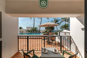 Un balcon avec vue sur la piscine, des sièges d’extérieur et une rambarde.