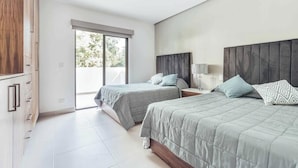 Une chambre moderne avec deux lits, une grande fenêtre et une porte coulissante donnant sur un espace extérieur.