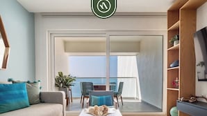 Una sala de estar moderna con un sofá, una mesa de centro y sillas. Hay un balcón con vistas.