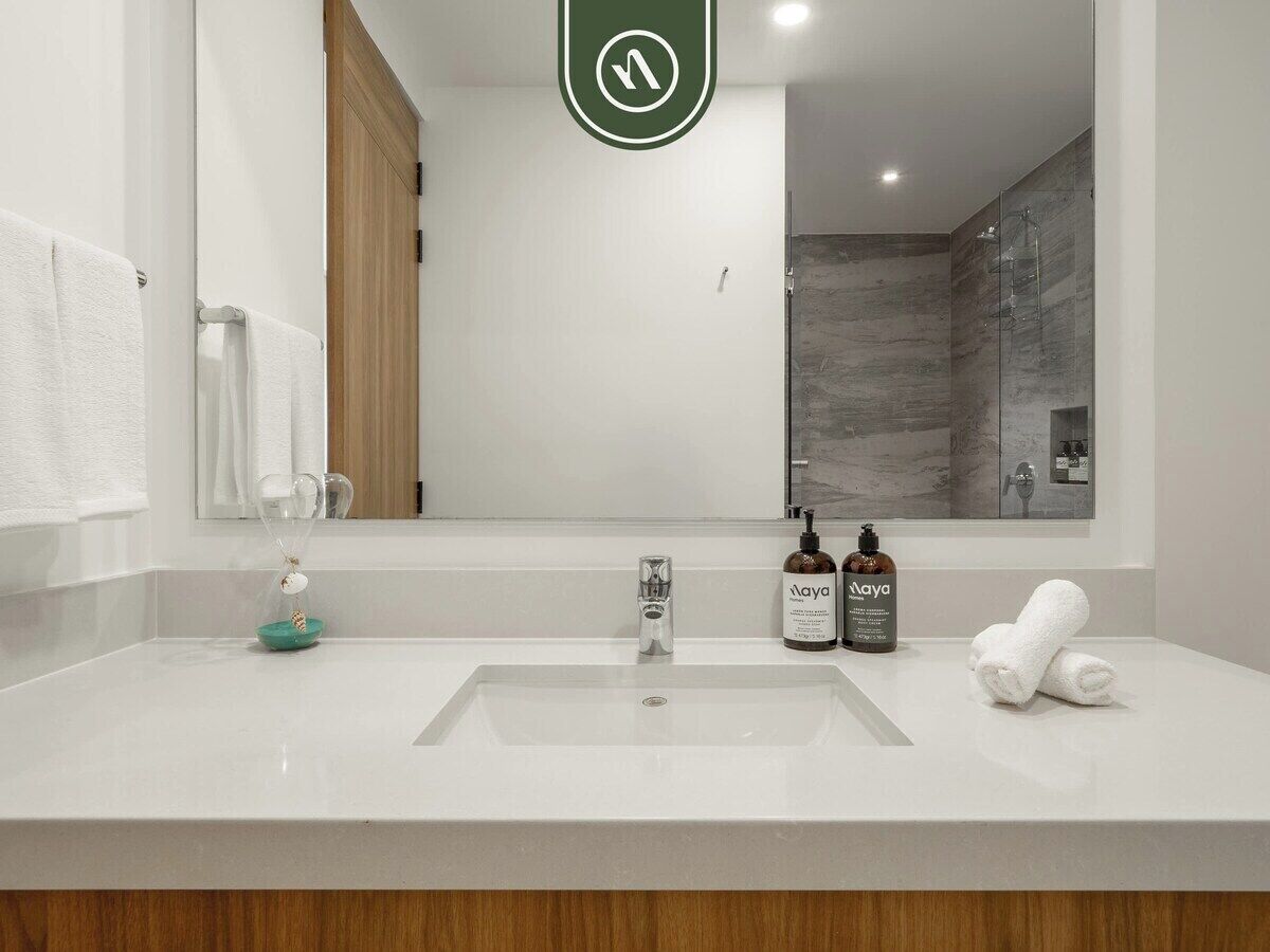 Un baño moderno con un espejo grande, un lavabo y una ducha.