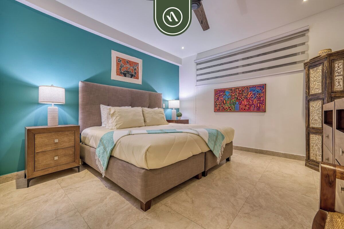 Une chambre à coucher avec un lit, des tables de chevet, une commode et des œuvres d’art accrochées aux murs.