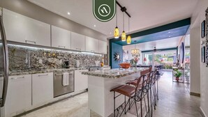 A modern kitchen with a marble backsplash, stainless steel appliances, and a bar area with stools.