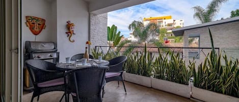 A balcony with a dining table and chairs, a grill, and decorative masks.