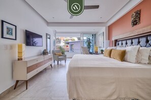 Une chambre à coucher comprenant un lit, une télévision, un canapé et un coin repas avec une table et des chaises.