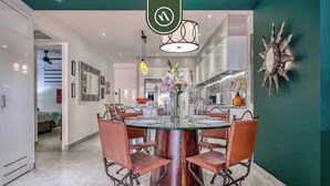 A modern dining area with a round glass table, leather chairs, and a central vase with flowers.