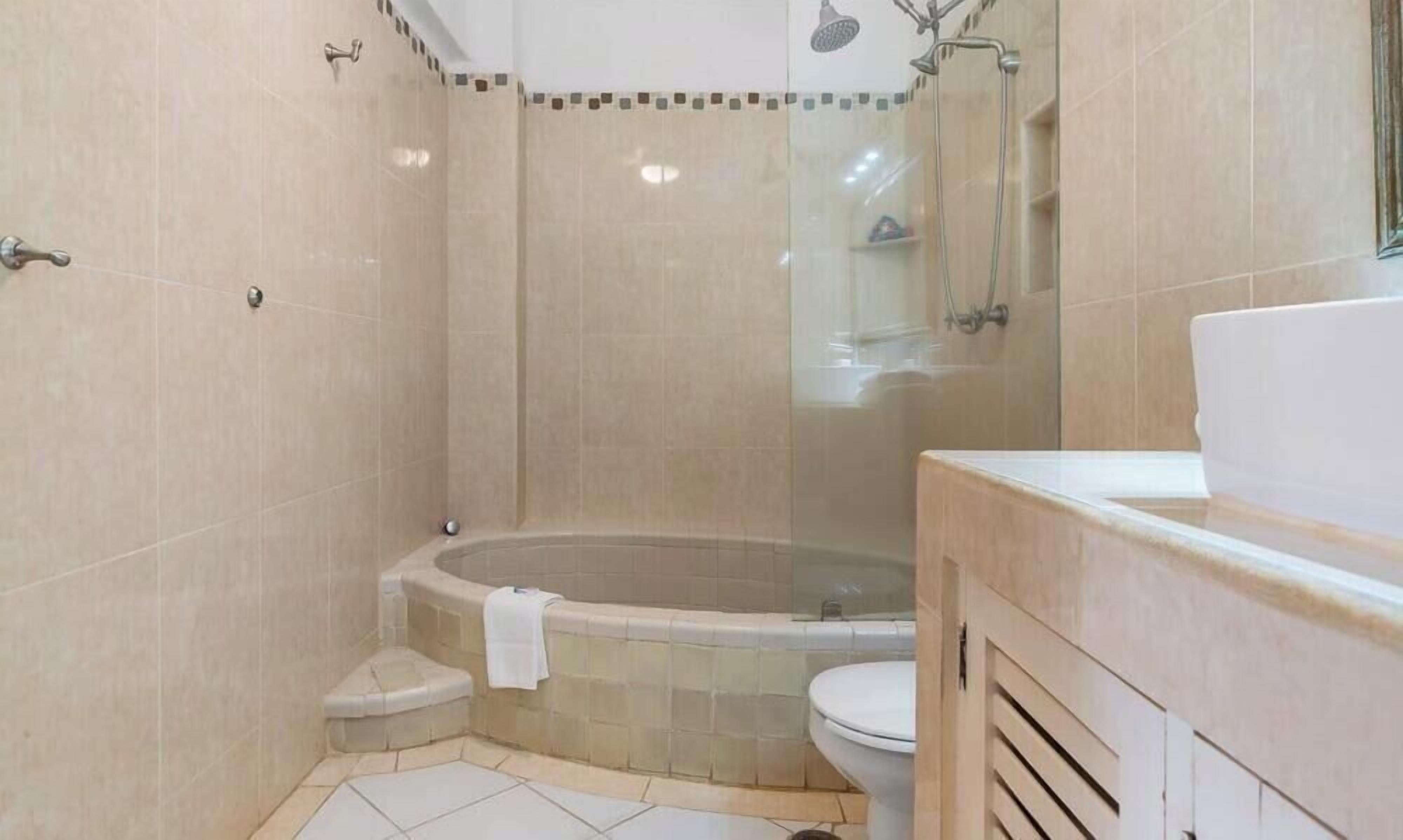 A bathroom with a bathtub, toilet, and shower area.
