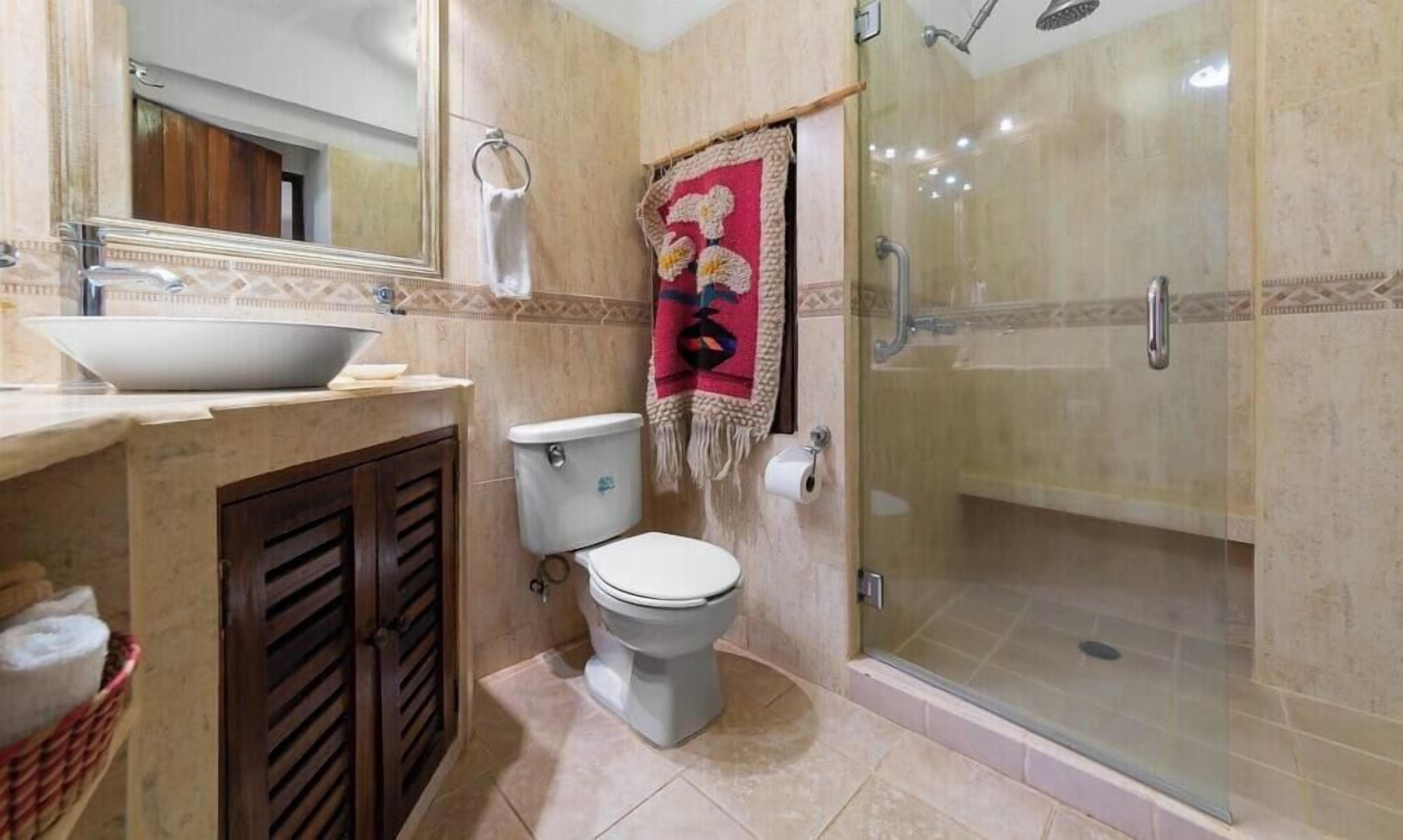 Une salle de bain équipée de toilettes, d’un lavabo, d’une douche et d’un miroir.