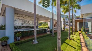 A modern outdoor area with a seating area, palm trees, and a well-maintained lawn. - Luxury 1 BR Condo in Pier 57 - Infinity Pool (Puerto Vallarta)