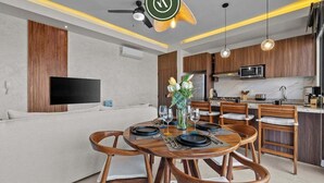 A modern kitchen with wooden cabinets, a built-in microwave, and a dining area with wooden chairs and a round table set for four.