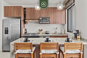 A modern kitchen with a built-in microwave, stainless steel refrigerator, and wooden cabinets.