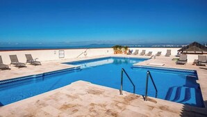 Une piscine sur le toit, avec une eau d’un bleu cristallin, entourée de chaises longues et offrant une vue sur l’océan.