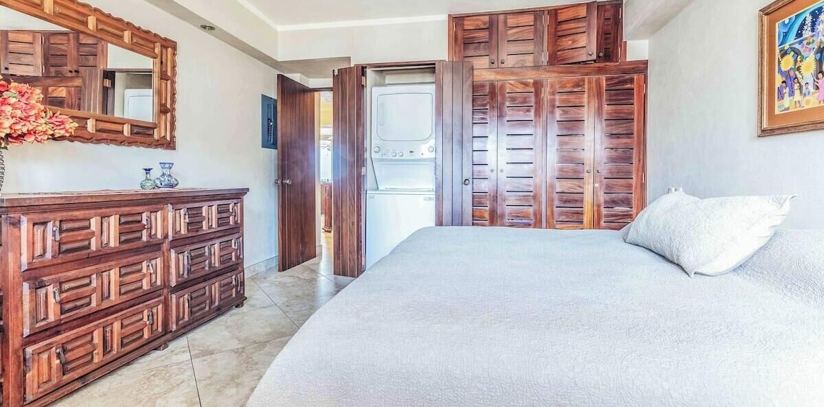 A bedroom with a bed, wooden wardrobe, and a mirror.