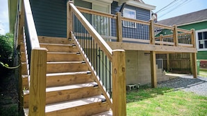 A wooden staircase leading to a deck with a railing.