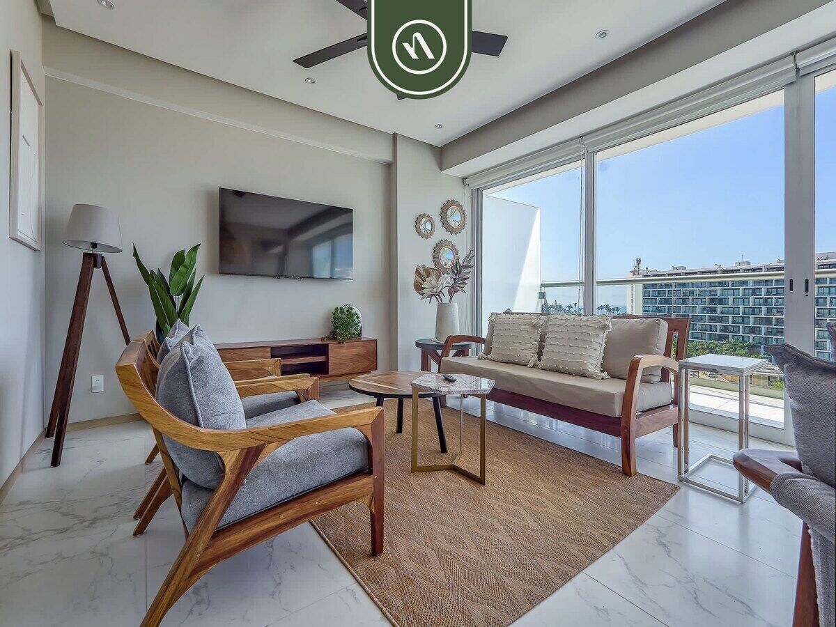 A modern living room with a sofa, chairs, a coffee table, and a TV.