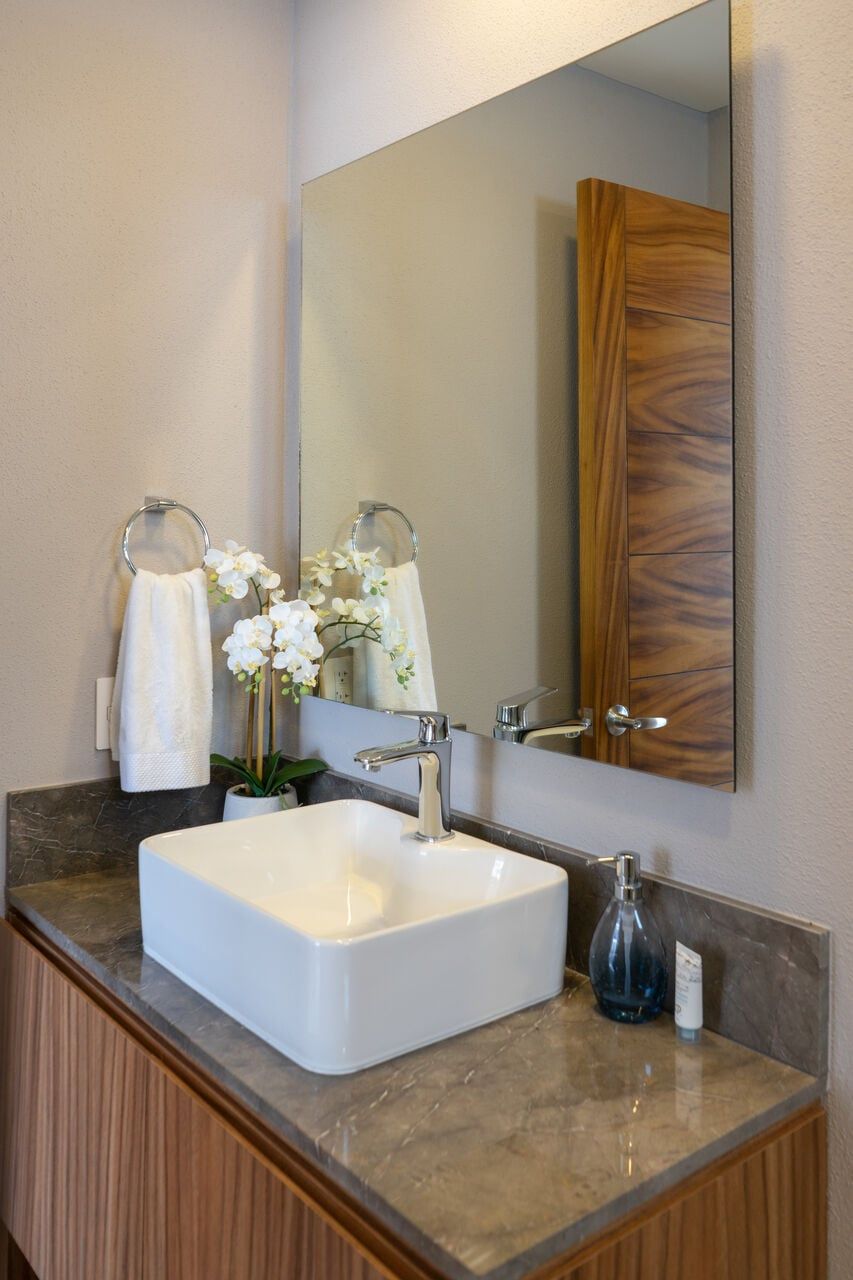 A bathroom with a white sink, a mirror, and a wooden door.