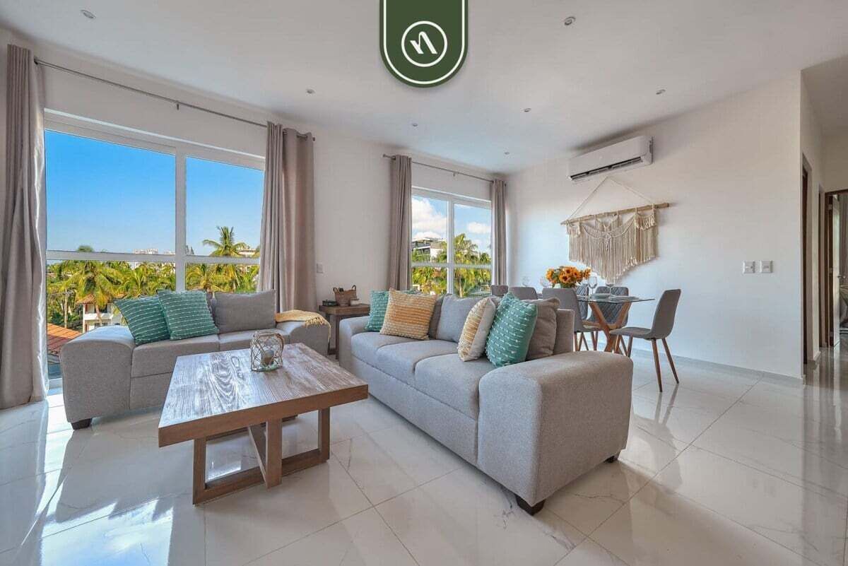 A modern living room with a sofa, coffee table, and dining area.