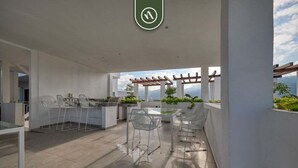 An outdoor patio area with a pergola, seating, and a view of the mountains. - Equipped 2BR Condo in Versalles - Pool - King Bed (Puerto Vallarta)